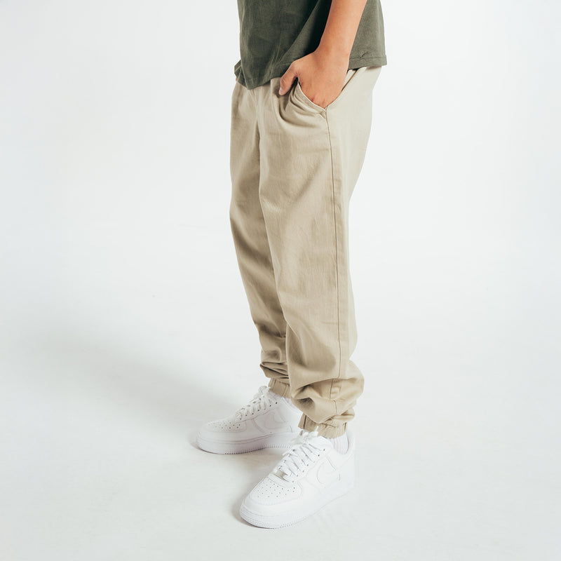 Youth woven jogger pants in light beige with side seam pockets and tapered leg