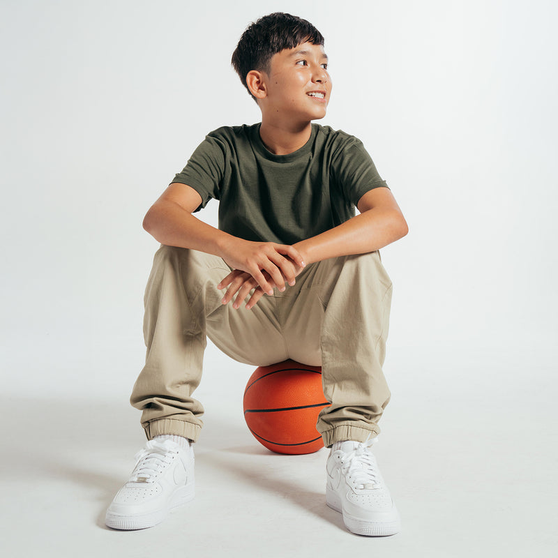 Youth woven jogger pants with elastic cuffs and relaxed tapered legs in light beige