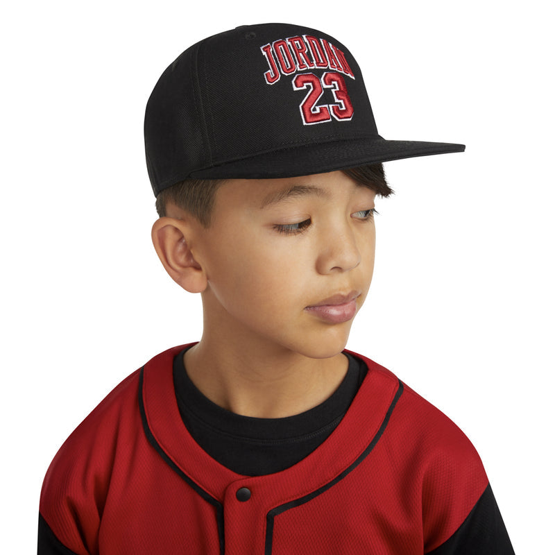 Black flatbrim snapback on child with red 'JORDAN 23' front lettering