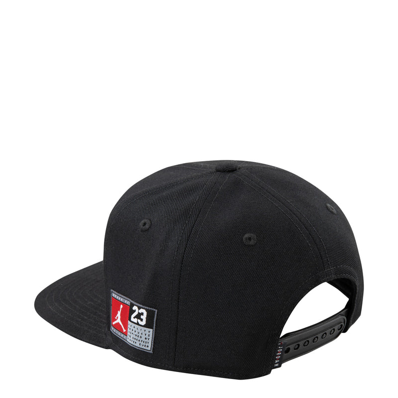 Black youth snapback cap with red-and-white side logo patch and flat brim