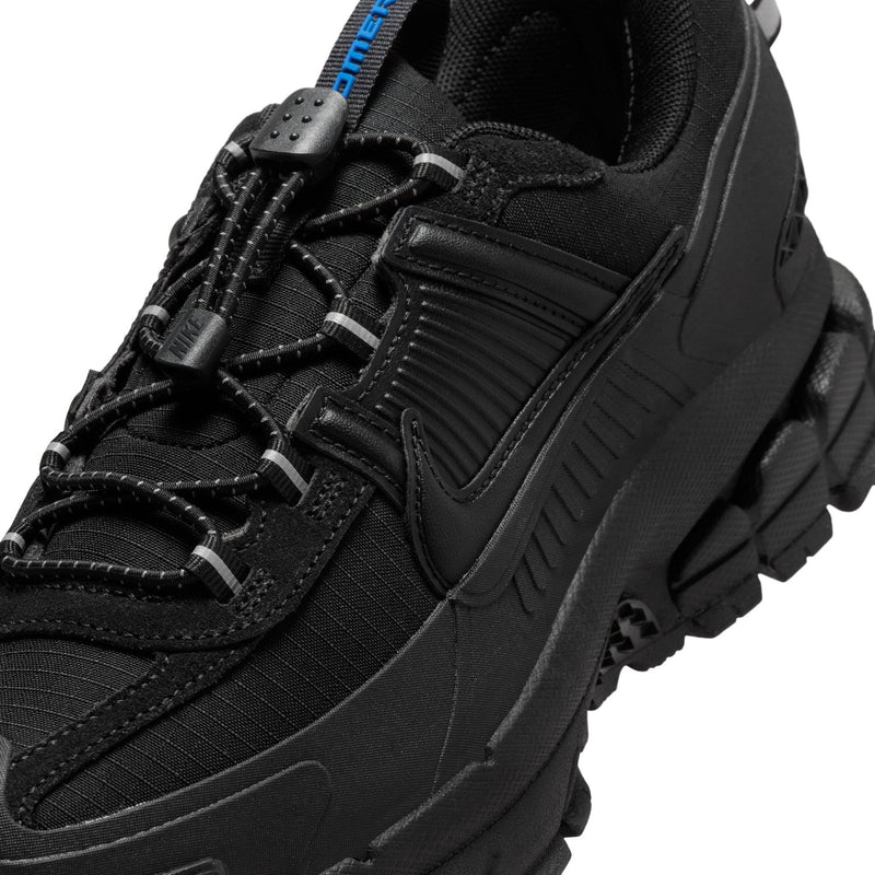 Women’s black trail shoes close-up with textured upper and blue tongue label