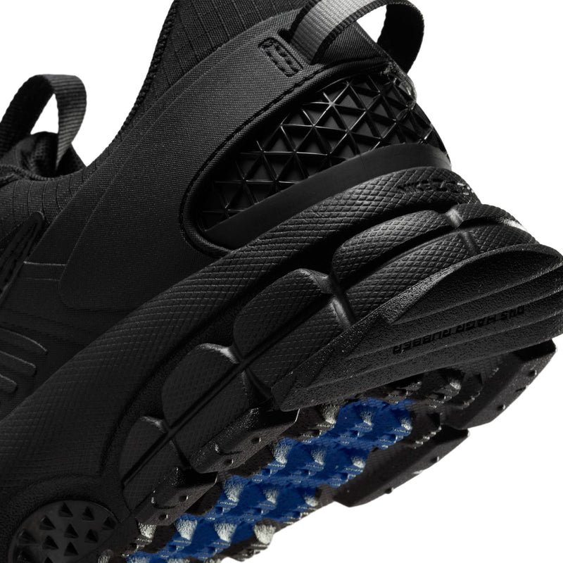 Women’s black trail shoe close-up with blue outsole traction and tread grooves